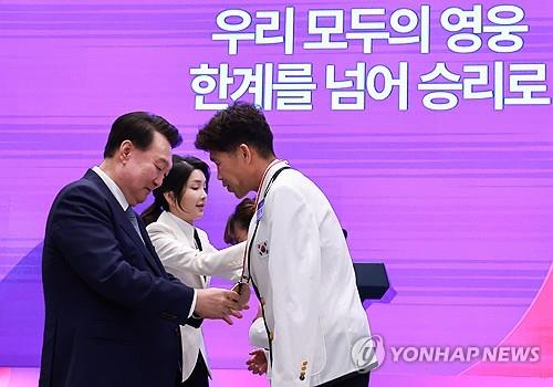 윤석열 대통령 부부, 파리 패럴림픽 김황태 선수 부부에게 국민감사 메달 수여 (서울=연합뉴스) = 윤석열 대통령과 김건희 여사가 13일 청와대 영빈관에서 열린 '2024 파리 패럴림픽 선수단 격려 오찬'에서 트라이애슬론 김황태 선수와 아내인 경기보조인 김진희 씨에게 국민감사 메달을 수여하고 있다.